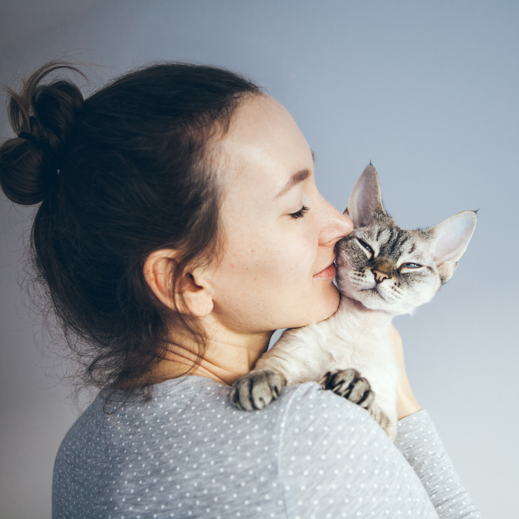 Woman hugging and nuzzling her cat.